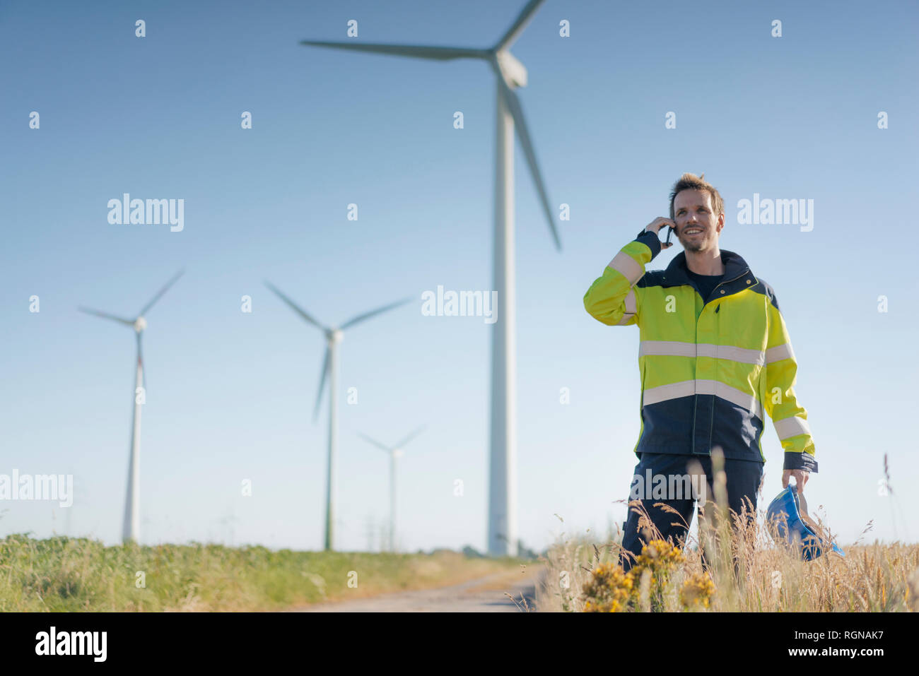 Lächelnd Ingenieur steht ein Feld an einem Windpark Gespräch am Handy Stockfoto