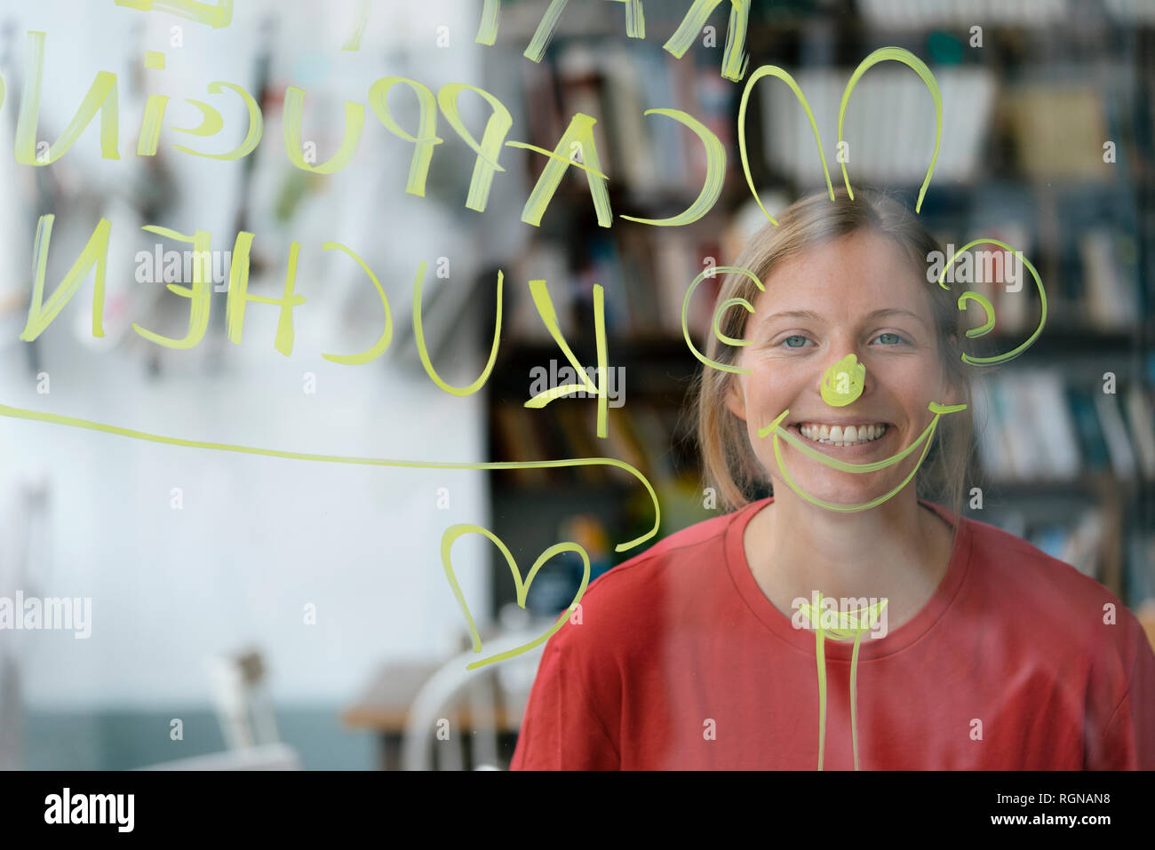 Porträt der glückliche junge Frau hinter Fensterglas in einem Cafe Stockfoto