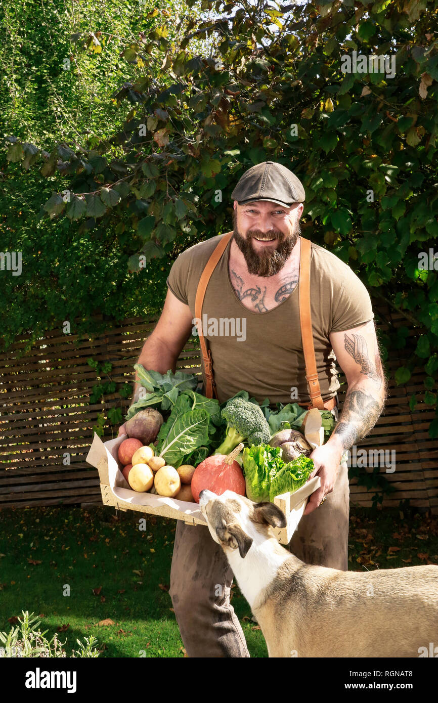 Reifer Mann die Kiste mit Gemüse in seinem Garten Stockfoto
