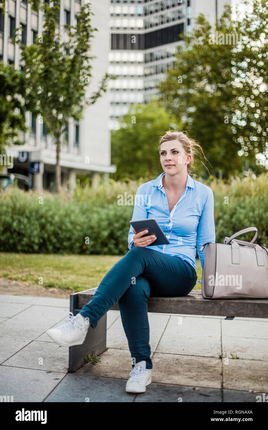 Frau sitzen auf einer Bank Holding tablet Stockfoto