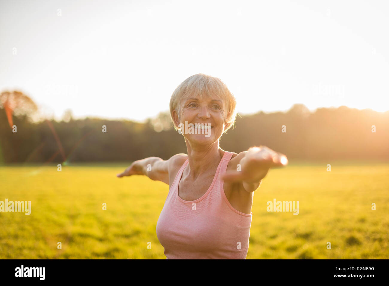 Portrait von lächelnden älteren Frau Yoga auf ländlichen Wiese bei Sonnenuntergang Stockfoto