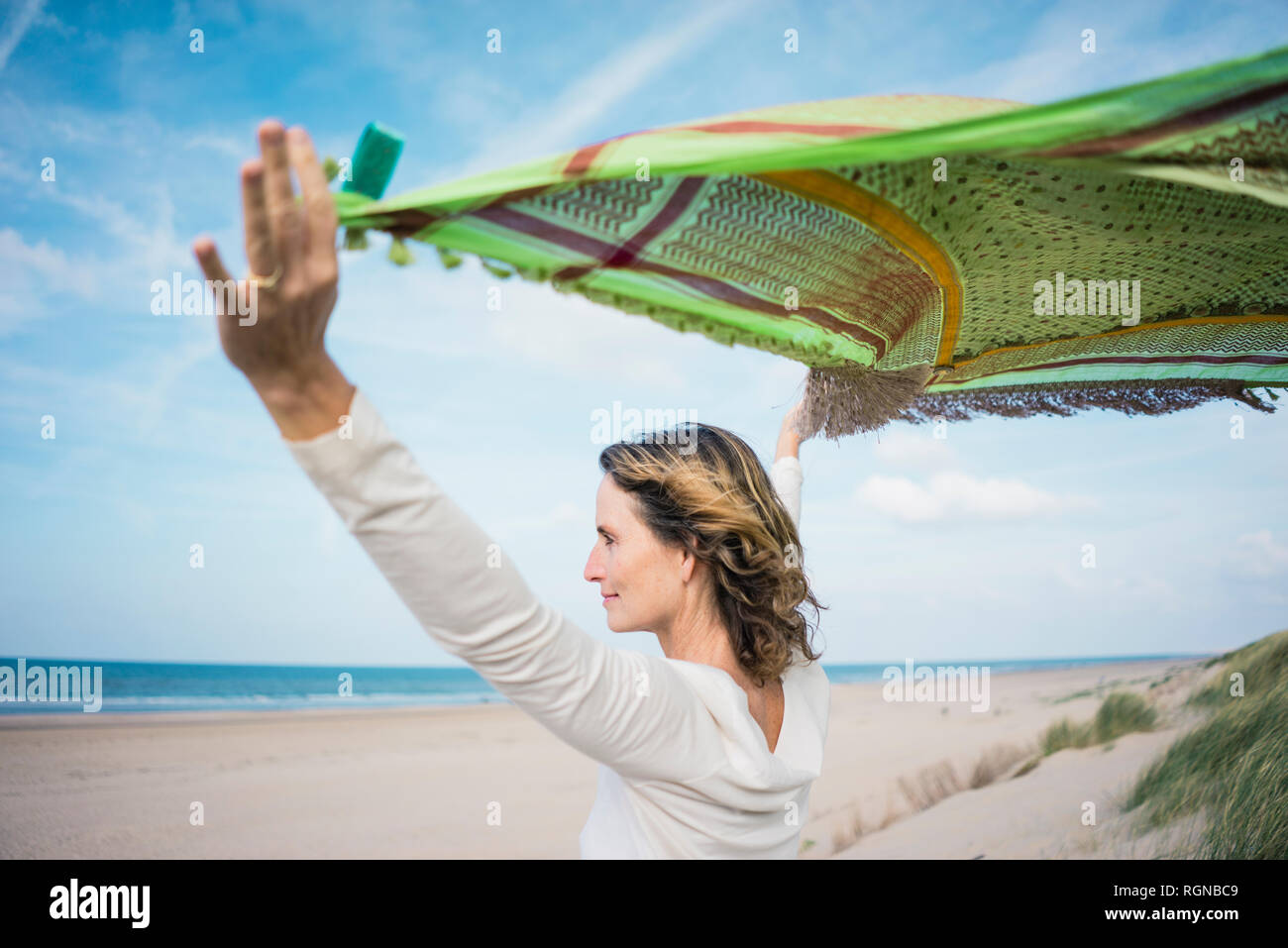 Reife Frau mit flatternden Schal im Wind, relxiang in den Dünen Stockfoto