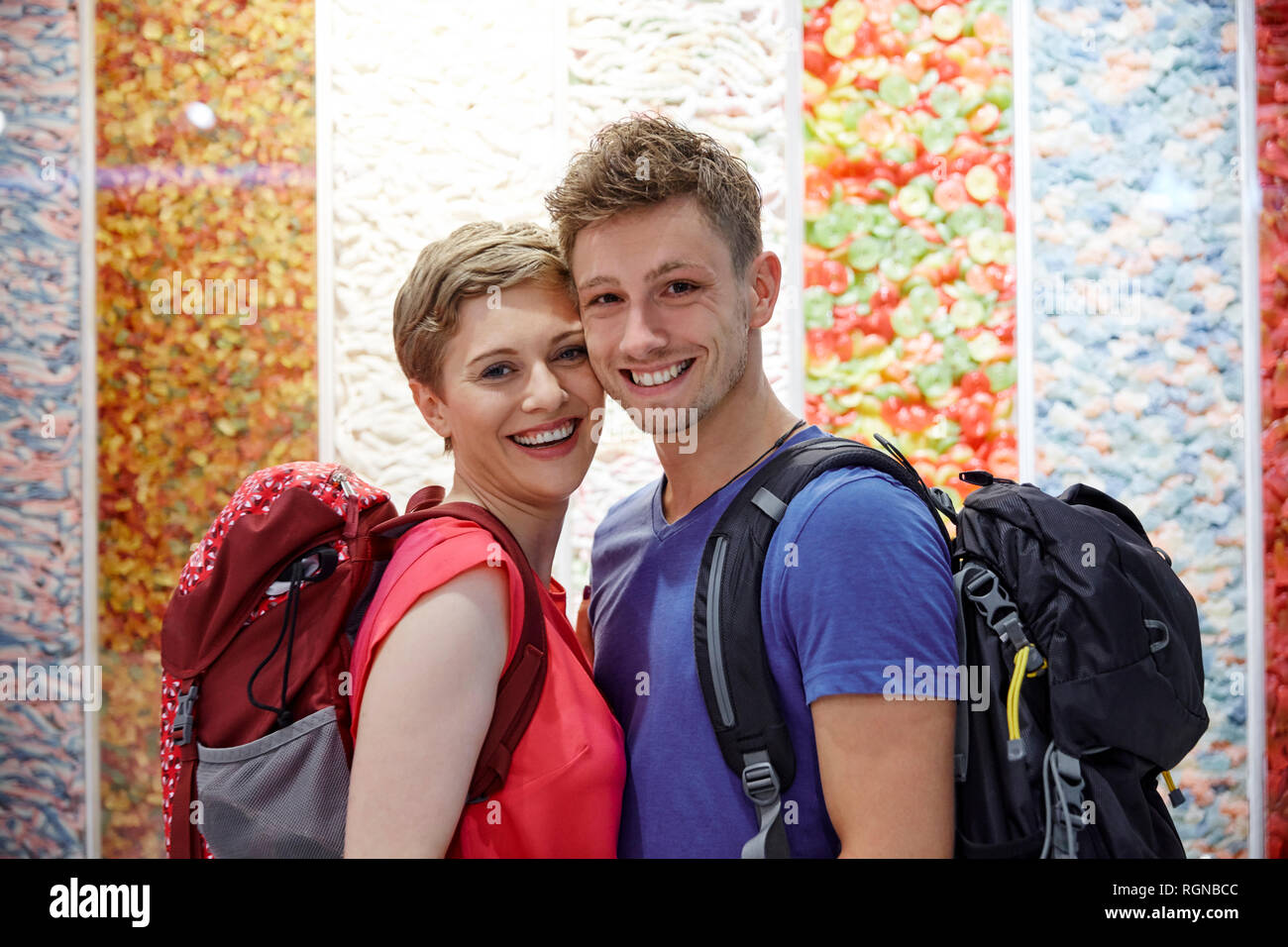 Portrait von glücklichen Paar mit Rucksäcken auf bunten Wand Stockfoto
