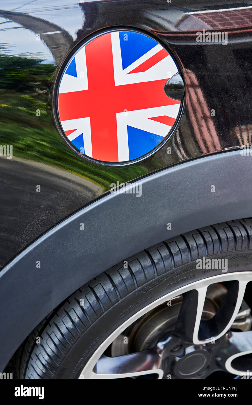 Nahaufnahme eines Runden tanken Kappe mit einer Gestaltung der nationalen Flagge von Großbritannien, durch schwarze glänzende auto Lack und Teil eines sportlichen Rad umgeben Stockfoto