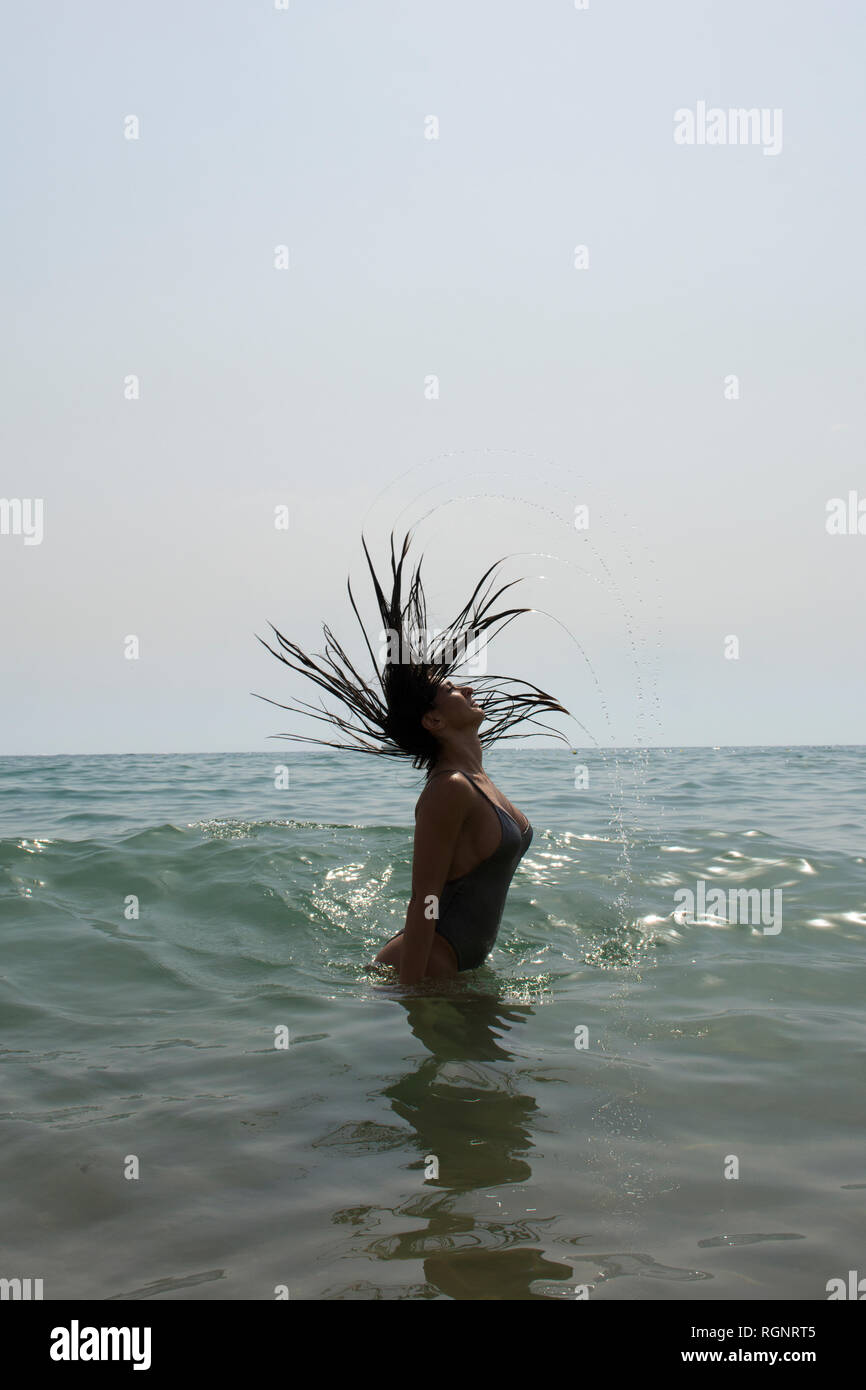 Junge Frau im Bikini Haar streichen im Meer Stockfoto