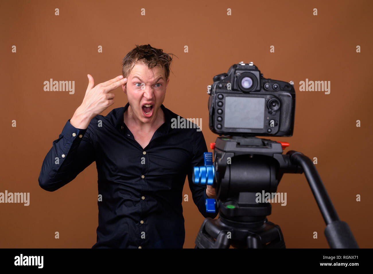 Junger Mann Einflussnehmer vlogging mit DSLR-Kamera im Studio, während sie lustiges Gesicht Stockfoto