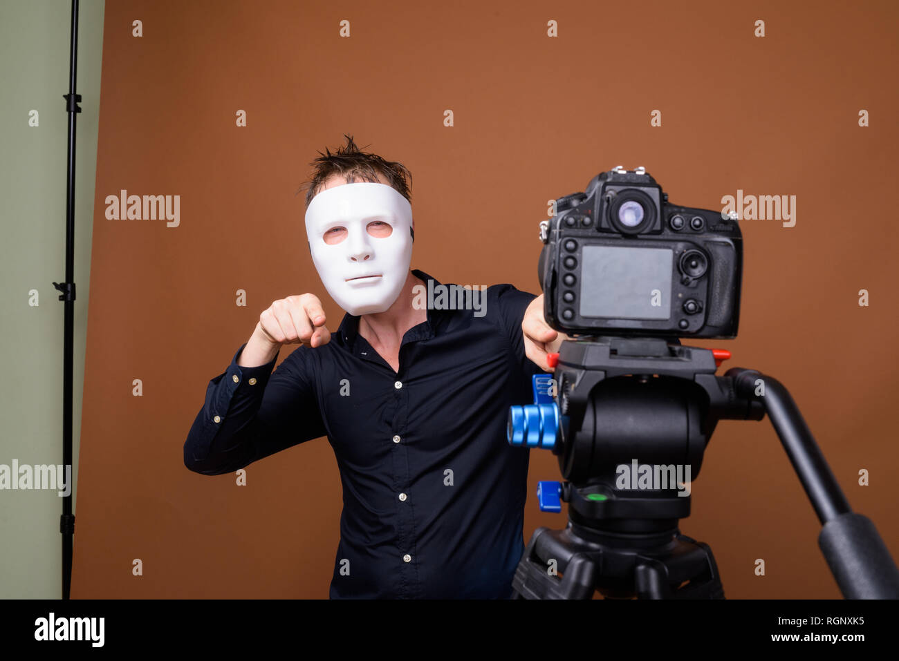 Junger Mann Einflussnehmer maskierter Während vlogging mit Kamera im Studio Stockfoto