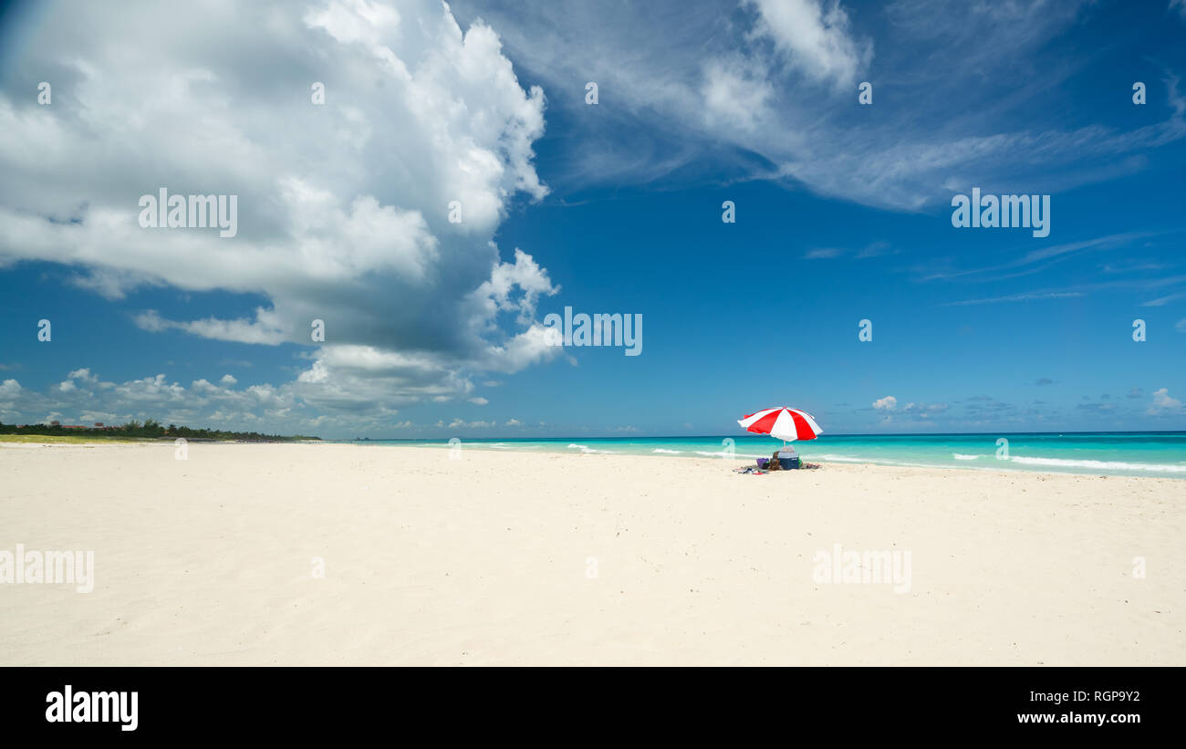 Großartiger Strand von Varadero, der an einem sonnigen Tag, feinen, weißen Sand und Türkis und Grün Karibische Meer, auf der rechten Seite einen roten Sonnenschirm, Kuba. Konzept Foto, c Stockfoto