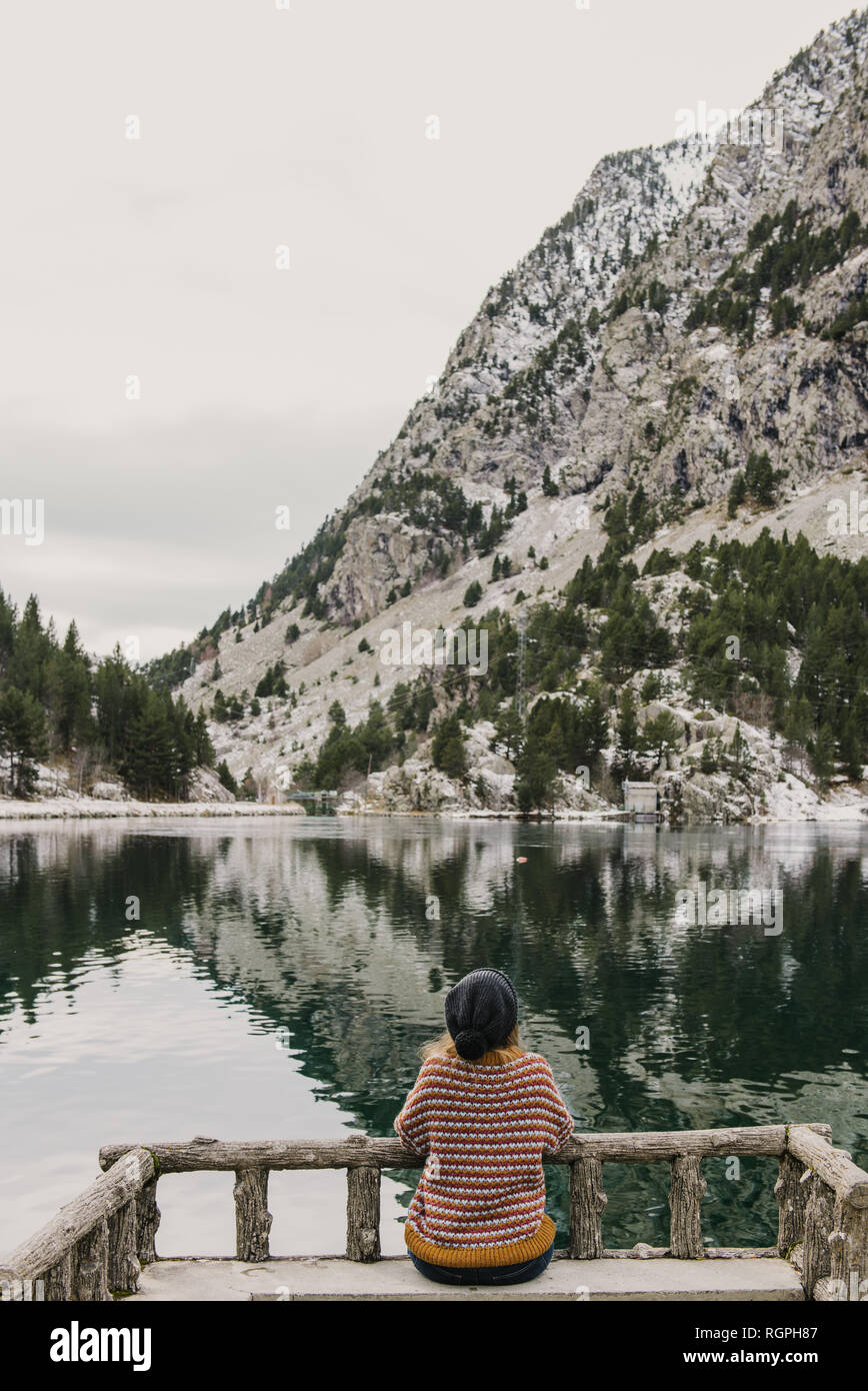 Heitere Frau mit geschlossenen Augen, die Yoga in Lotus-Pose während der Meditation auf Felsen am Meer macht Stockfoto