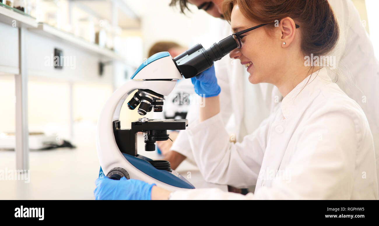 Junge Wissenschaftler durch Mikroskop im Labor auf der Suche Stockfoto