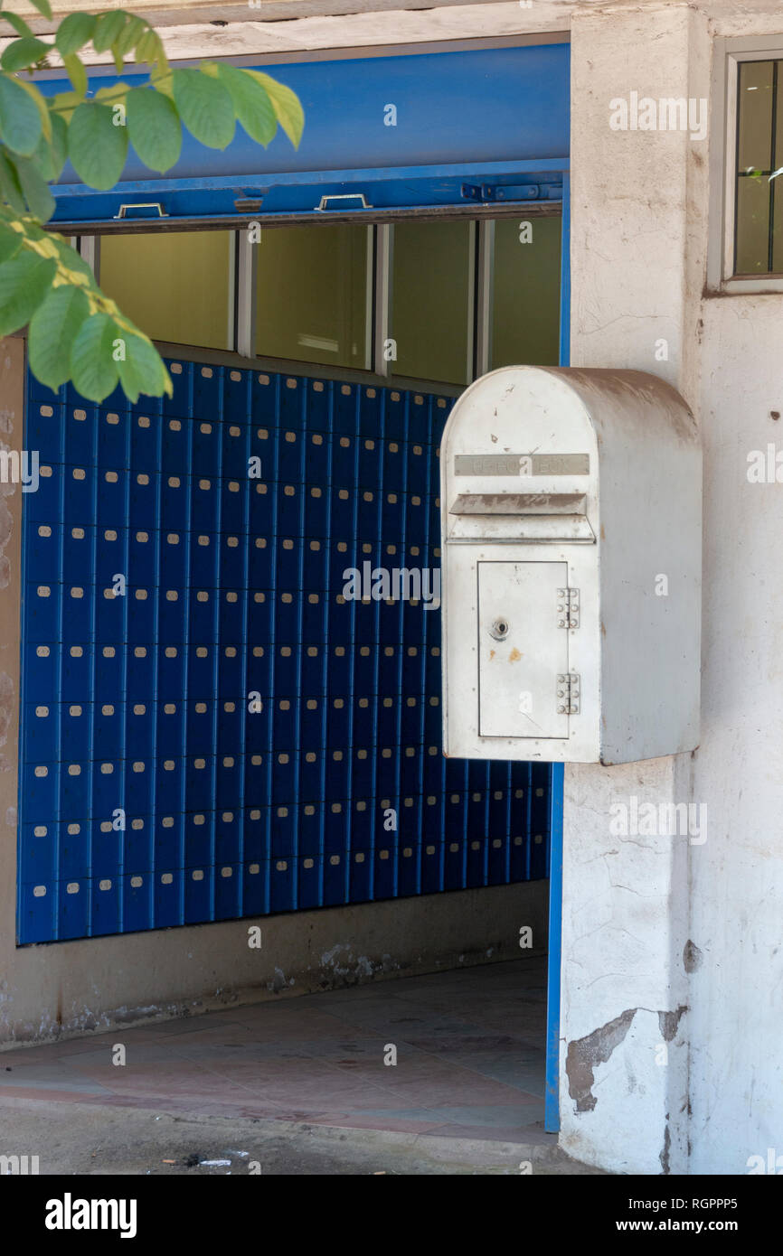 Eine Vorderansicht eines weißen Metall verschmutzt Post Box, die an die Wand außerhalb einer Post verschraubt ist Stockfoto