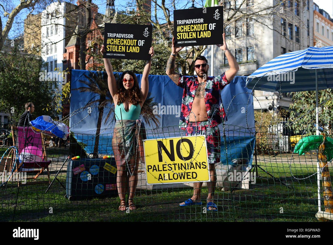 Zwei Modelle stehen auf einem "stacheldraht Beach' außerhalb des Büros von TripAdvisor in Soho Square, Central London, als Teil einer Kampagne von Amnesty International fordert die Unternehmen und anderen Unternehmen zu stoppen Auflistung Zimmer und Aktivitäten in israelischen Siedlungen in den palästinensischen Gebieten. Stockfoto