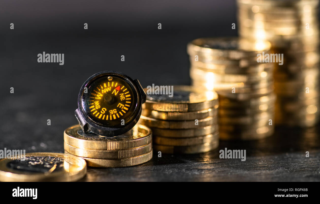 Nadel eines Kompasses weist auf steigende Stapel von Münzen Stockfoto