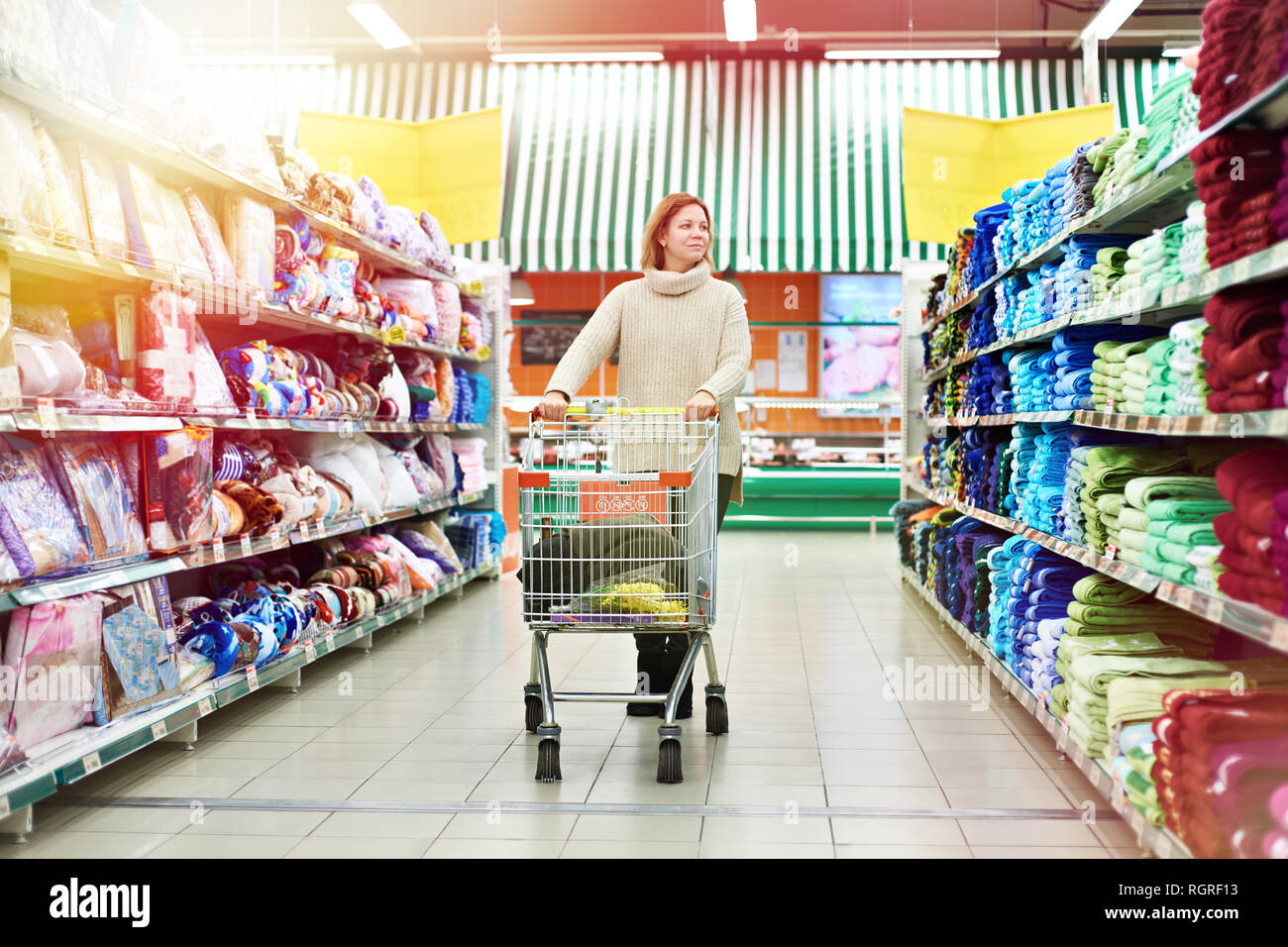 Frau Shopper mit Warenkorb wählt Produkte im Shop Stockfoto