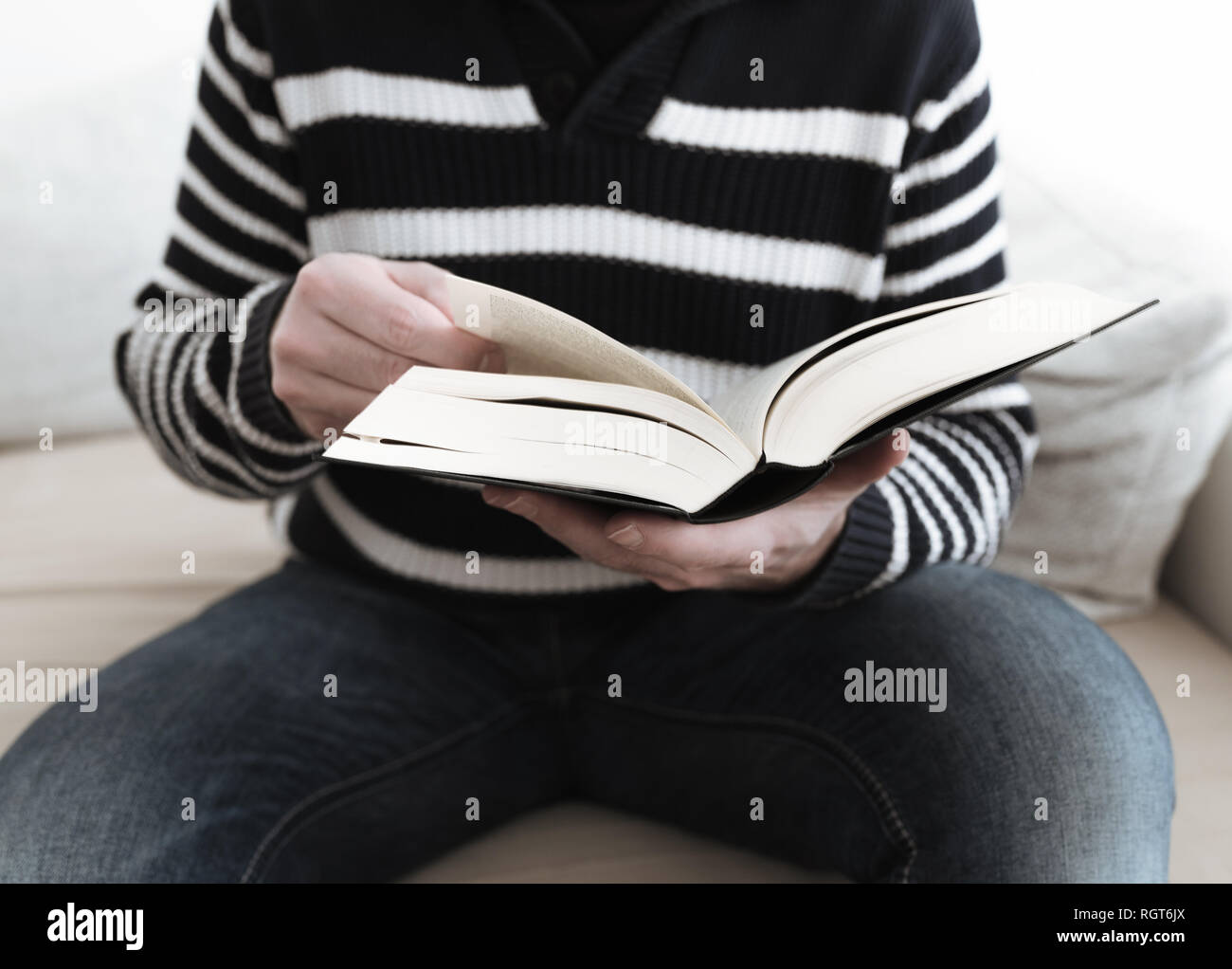 Mann sitzt auf einem Sofa mit einem Buch Stockfoto