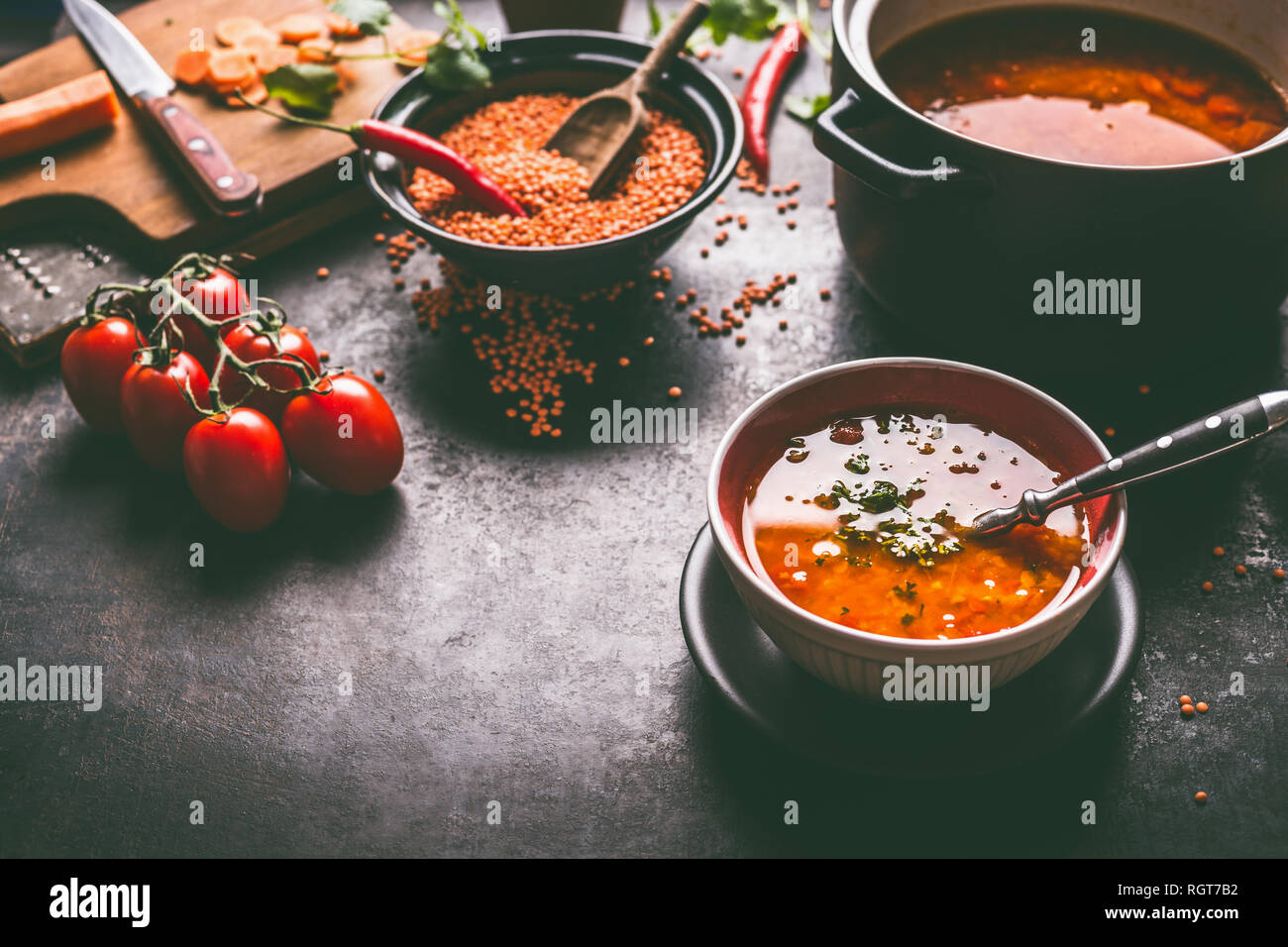 Gesund vegan Linsensuppe in der Schüssel mit Löffel auf dunklen Küche Tisch Hintergrund mit Zutaten. Vegetarisches Essen. Saubere Diät essen. Quelle der Anlage ba Stockfoto