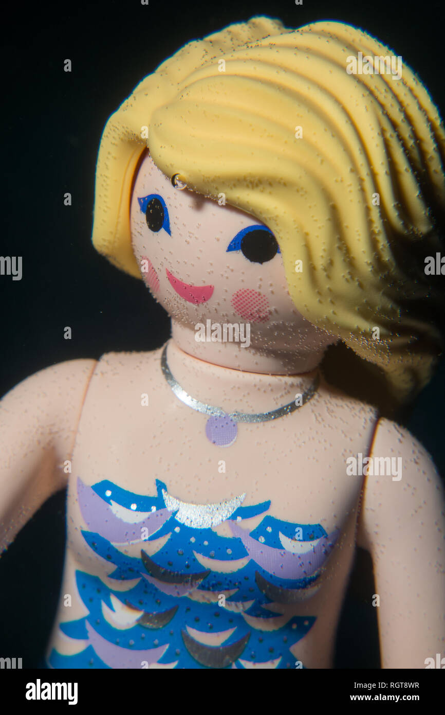Mermaid Spielzeug Puppe spielen mobil mit Blasen im Gesicht. Unterwasser Foto, schwarz Wasser Technik. Stockfoto