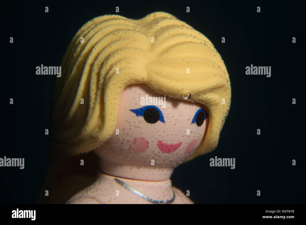 Mermaid Spielzeug Puppe spielen mobil mit Blasen im Gesicht. Unterwasser Foto, schwarz Wasser Technik. Stockfoto