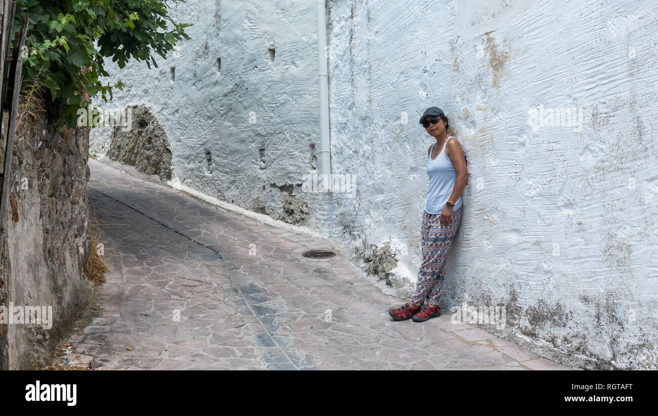 Frau zu Fuß durch die Straßen der griechischen Dorf mit Hut und Tank Top Stockfoto