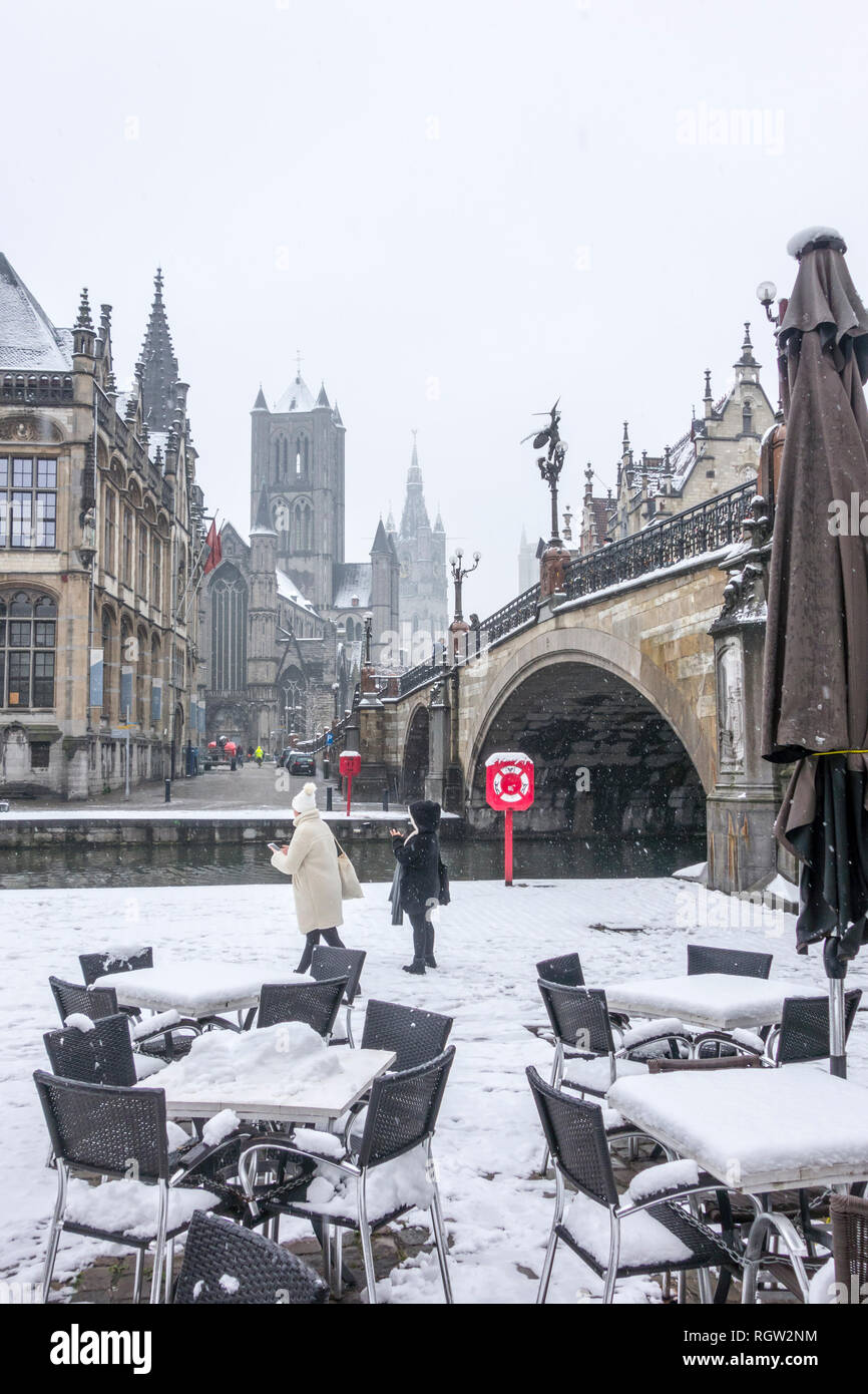 Leere Cafe und Touristen, die die Stadt Gent bei Schnee Dusche in der Nebensaison im Winter, Ostflandern, Belgien Stockfoto