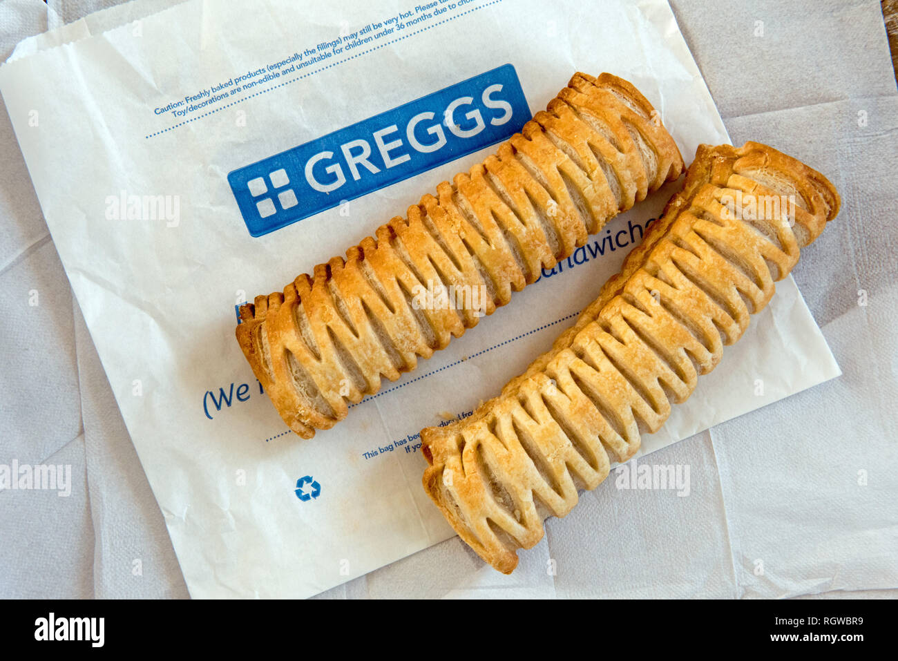 Zwei Greggs vegane Wurst rollen auf Paper Bag mit papierservietten hinter sich. Stockfoto