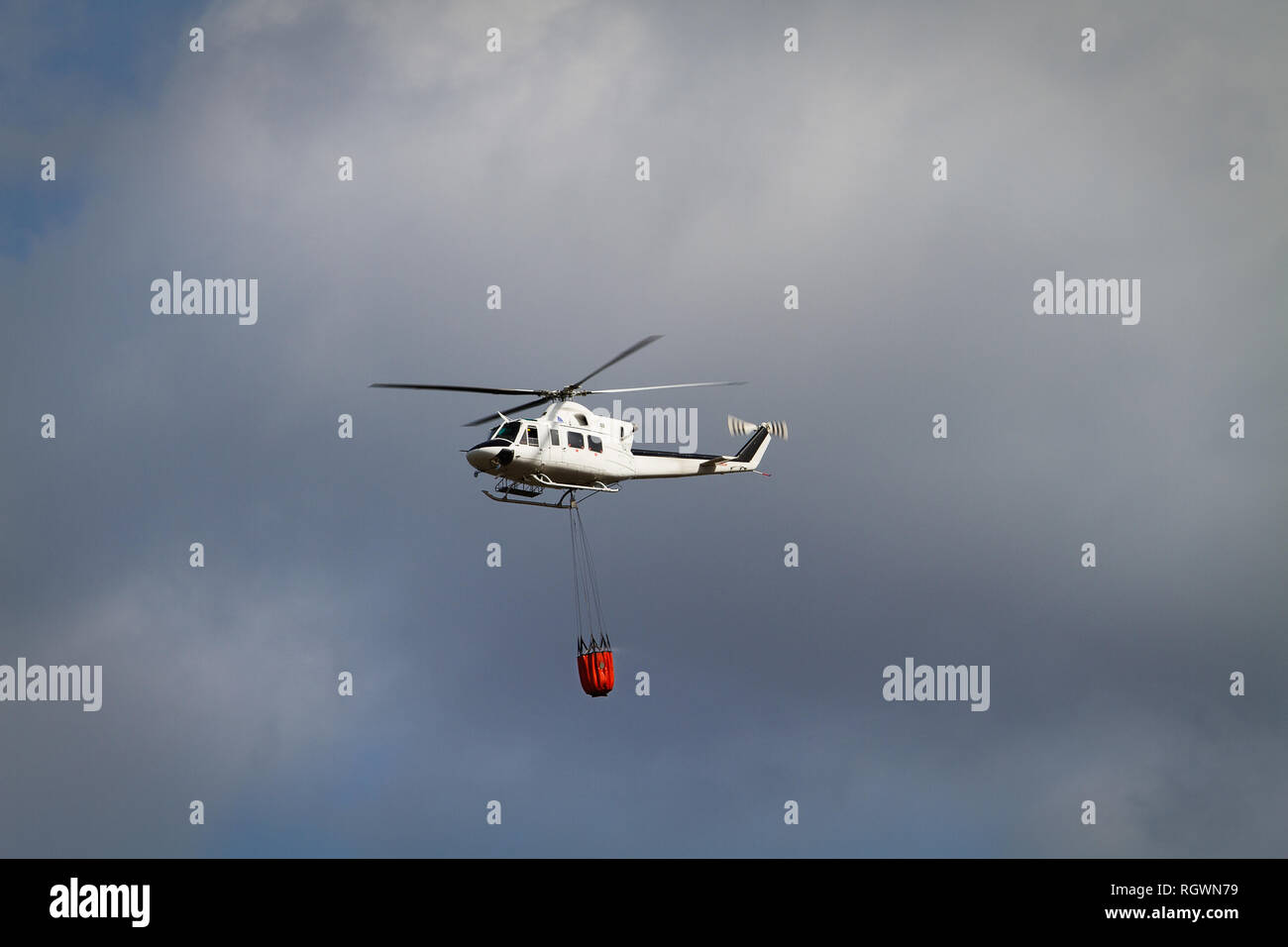 Die Brandbekämpfung Helikopter mit Bambi Korb mit Wasser auf dem Weg zu einem Brand geladen Stockfoto