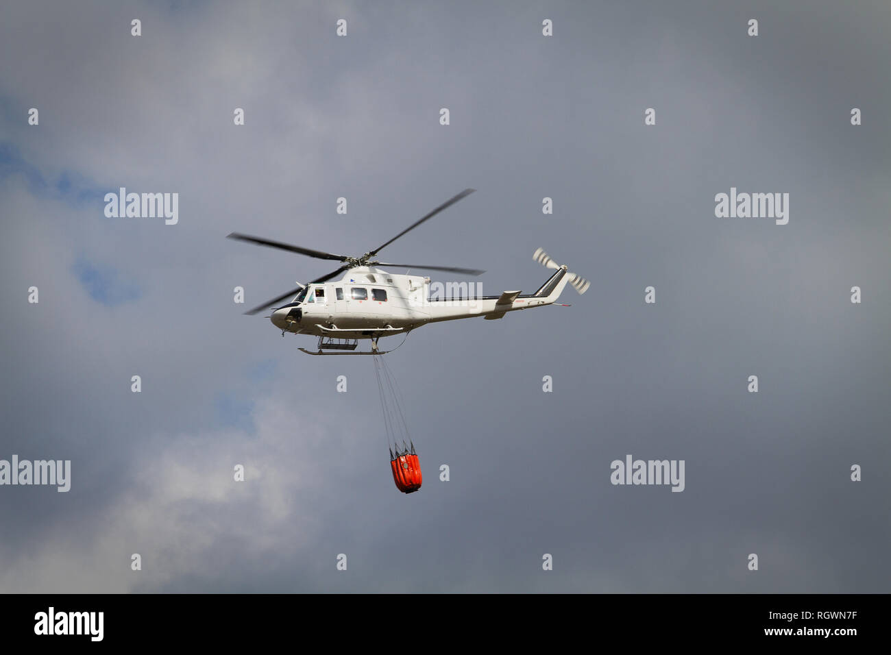 Die Brandbekämpfung Helikopter mit Bambi Korb mit Wasser auf dem Weg zu einem Brand geladen Stockfoto