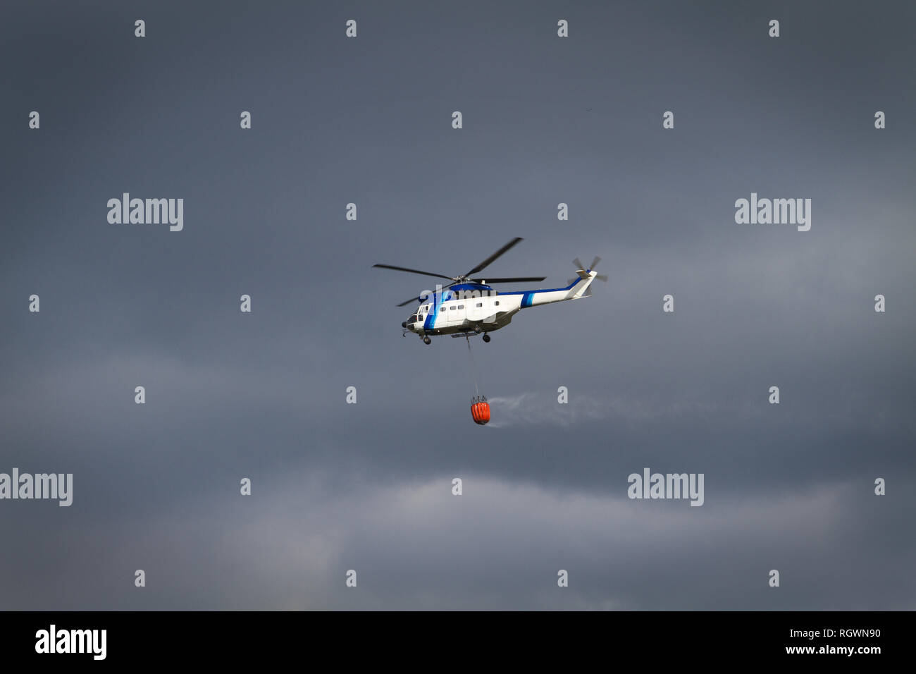 Die Brandbekämpfung Helikopter mit Bambi Korb mit Wasser auf dem Weg zu einem Brand geladen Stockfoto