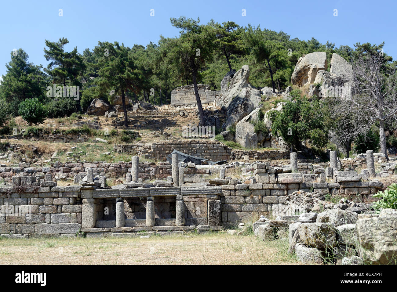 Die dorischen Säulen und Haus, das in die Wand des Tempels Terrasse gesetzt ist. Labraunda, Türkei. Stockfoto