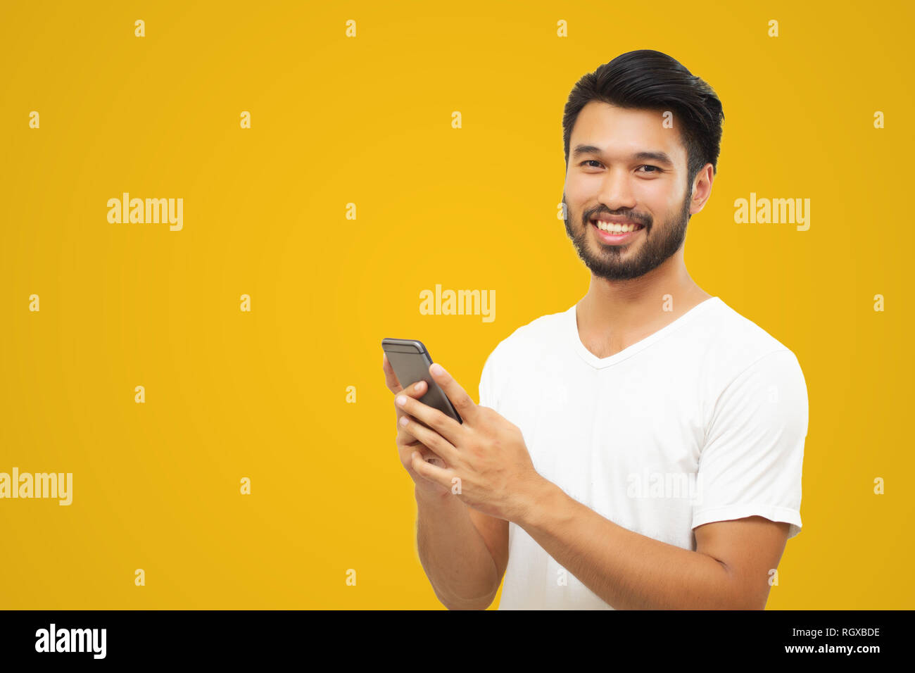 Asiatische Geschäftsmann stattlicher Mann mit einem Schnurrbart, zu lächeln und zu lachen und mit smart phone auf gelbem Hintergrund Stockfoto