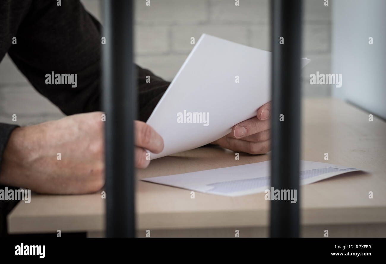 Ein gefangener hinter Gittern lesen einen Brief Stockfoto