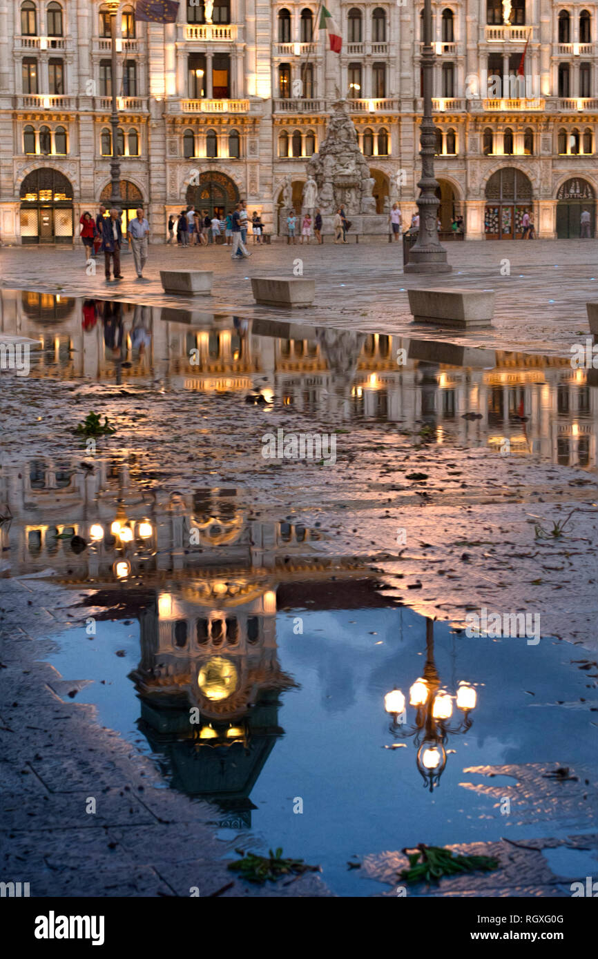 Triest. Italien. Die Glocke und der Uhrturm in einer großen Pfütze nach einem starken Regen nieder. Stockfoto