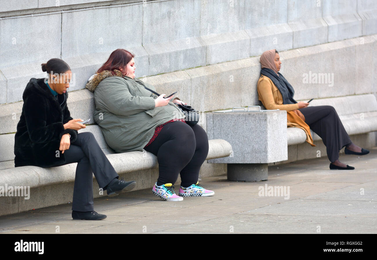 London, England, UK. Frauen in verschiedenen Größen auf ihre Handys suchen, Trafalgar Square [kein Modell Release] Stockfoto