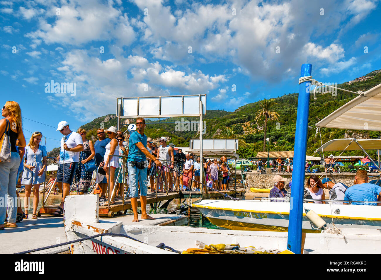 Korfu, Griechenland - 20. September 2018: eine Tour boot Führer hält die Boote im Dock als Touristen Line up auf Palaiokastritsa Strand auf der Insel Korfu Stockfoto