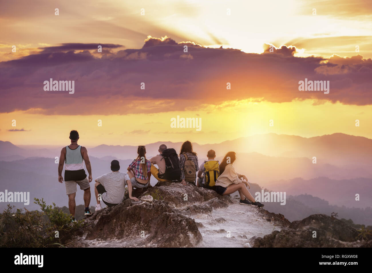 Große Gruppe von Freunden steht auf einem Berg und blickt auf den wunderschönen Sonnenuntergang. Reisen mit Freunden Konzept Stockfoto