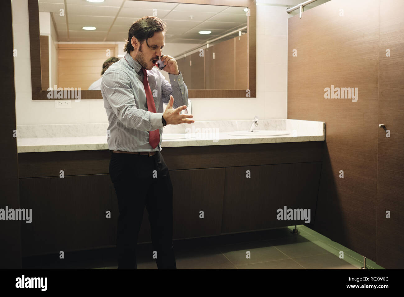 Wütend Business Mann schreiend auf Handy im Büro Toilette Stockfoto