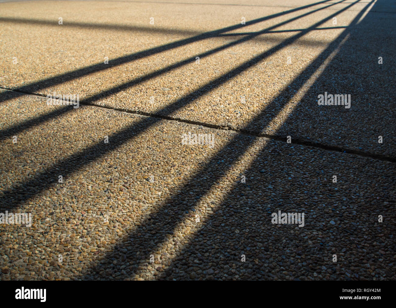 Schatten von Stahl Zaun auf grobe anti veredelt - Betonboden Schlupf Stockfoto