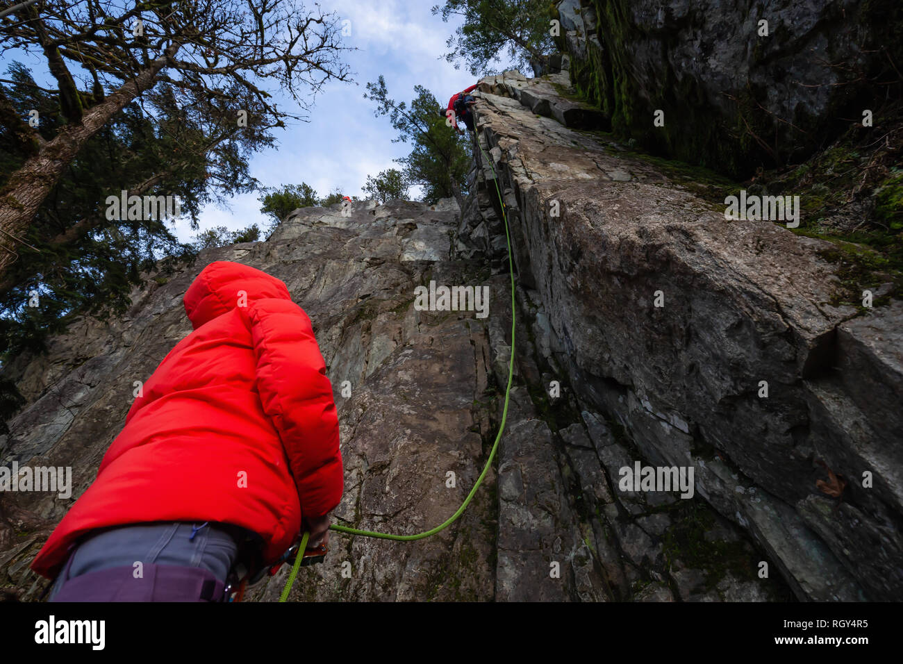 Kletterer sichern, während Ihr Partner Klettern am Rand der Klippe ist. In Area 44 in der Nähe von Squamish und Whistler, nördlich von Vancouver, BC, können Stockfoto