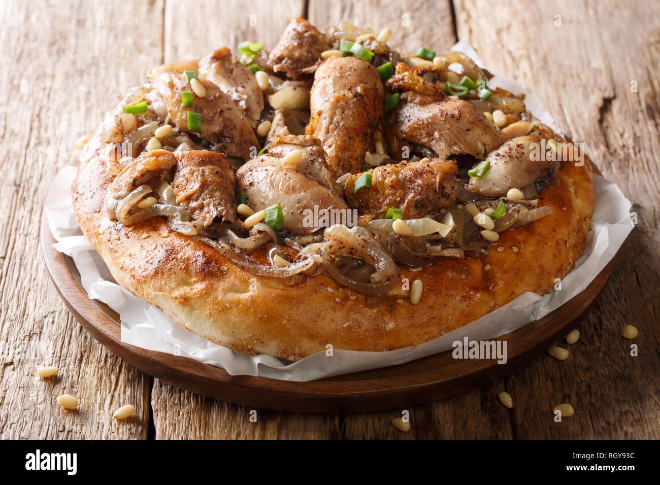 Im Nahen und Mittleren Osten Mahlzeit vom Huhn mit Sumach, Pinienkernen und Zwiebeln auf eine flache Brot Nahaufnahme auf dem Tisch. Horizontale Stockfoto