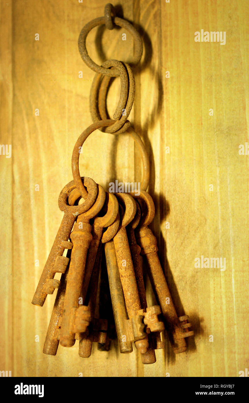 Haufen alter verrosteter Schlüssel hängen an einer Holzwand Stockfoto