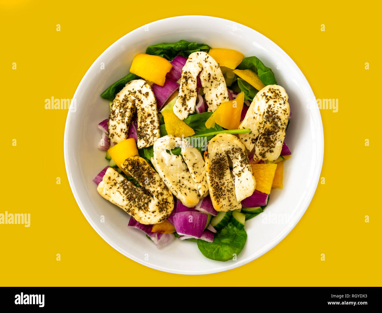 Halloumi Salat in einer weißen Schüssel auf gelbem Hintergrund Stockfoto