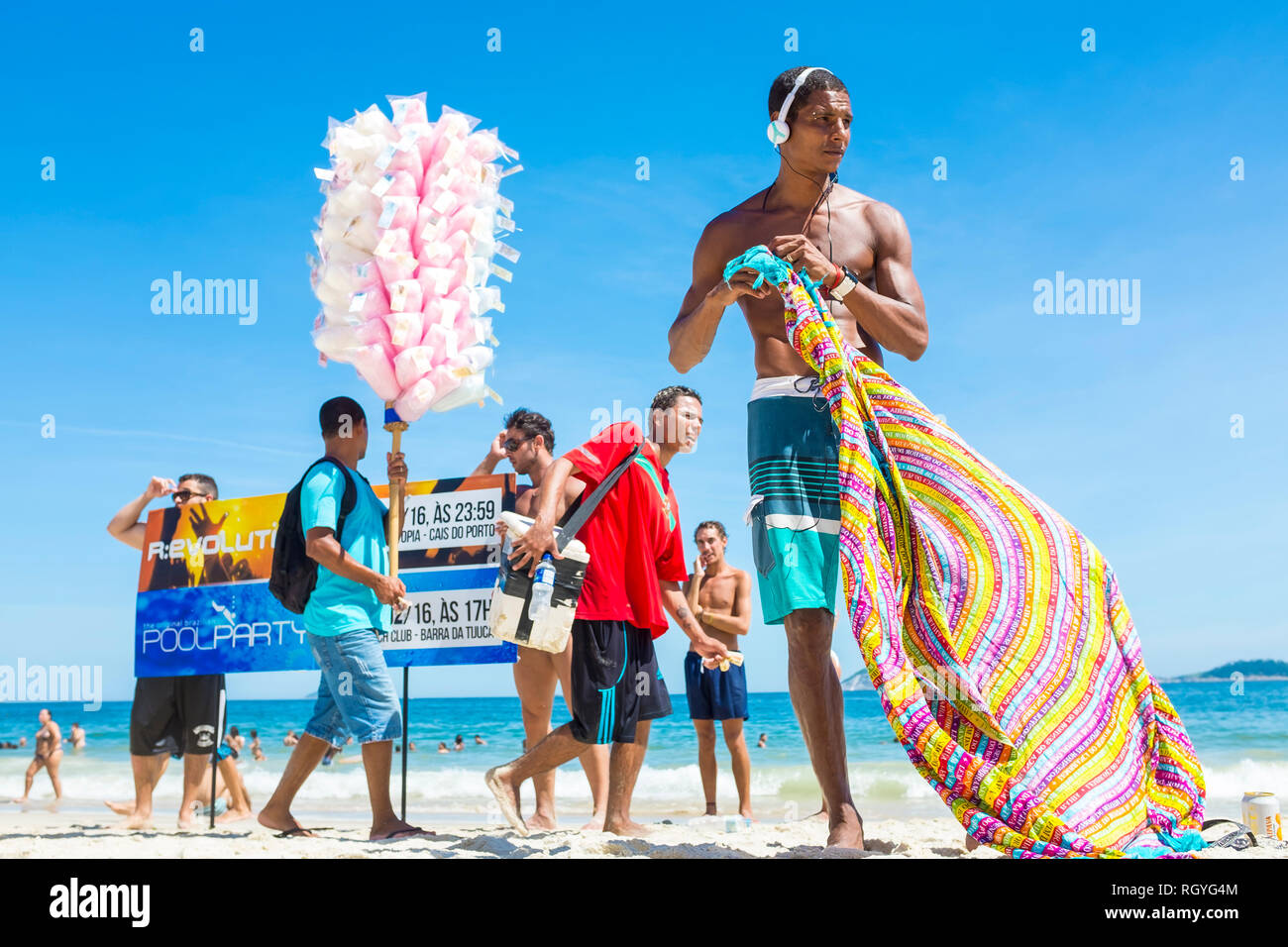 RIO DE JANEIRO - Februar, 2018: Projektträger holding Anzeichen für Pool Parteien und Verkäufer, Zuckerwatte unter Badegäste am Strand von Ipanema entfernt. Stockfoto