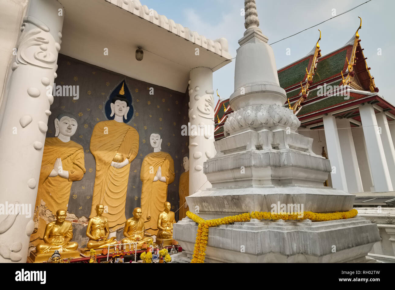 Ein Wandgemälde von Buddha und seine Jünger, neben einem weissen chedi oder Stupa, Wat Ratchanadta, Bangkok, Thailand Stockfoto