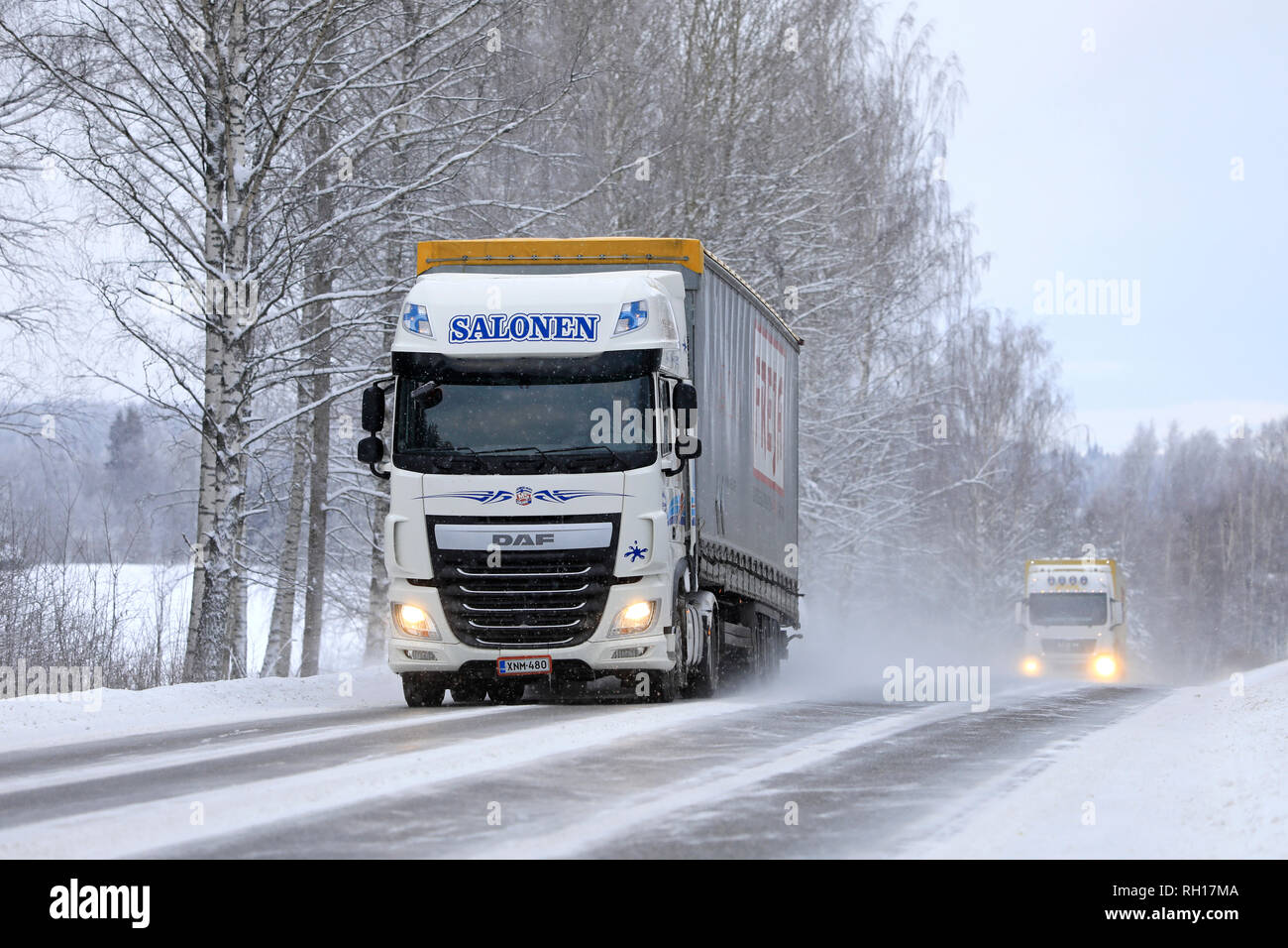 Salo, Finnland - Januar 27, 2019: Zwei weiße Auflieger Lkw, DAF XF Salonen im vorderen, schleppen waren auf Landstraße in Schneefall. Stockfoto