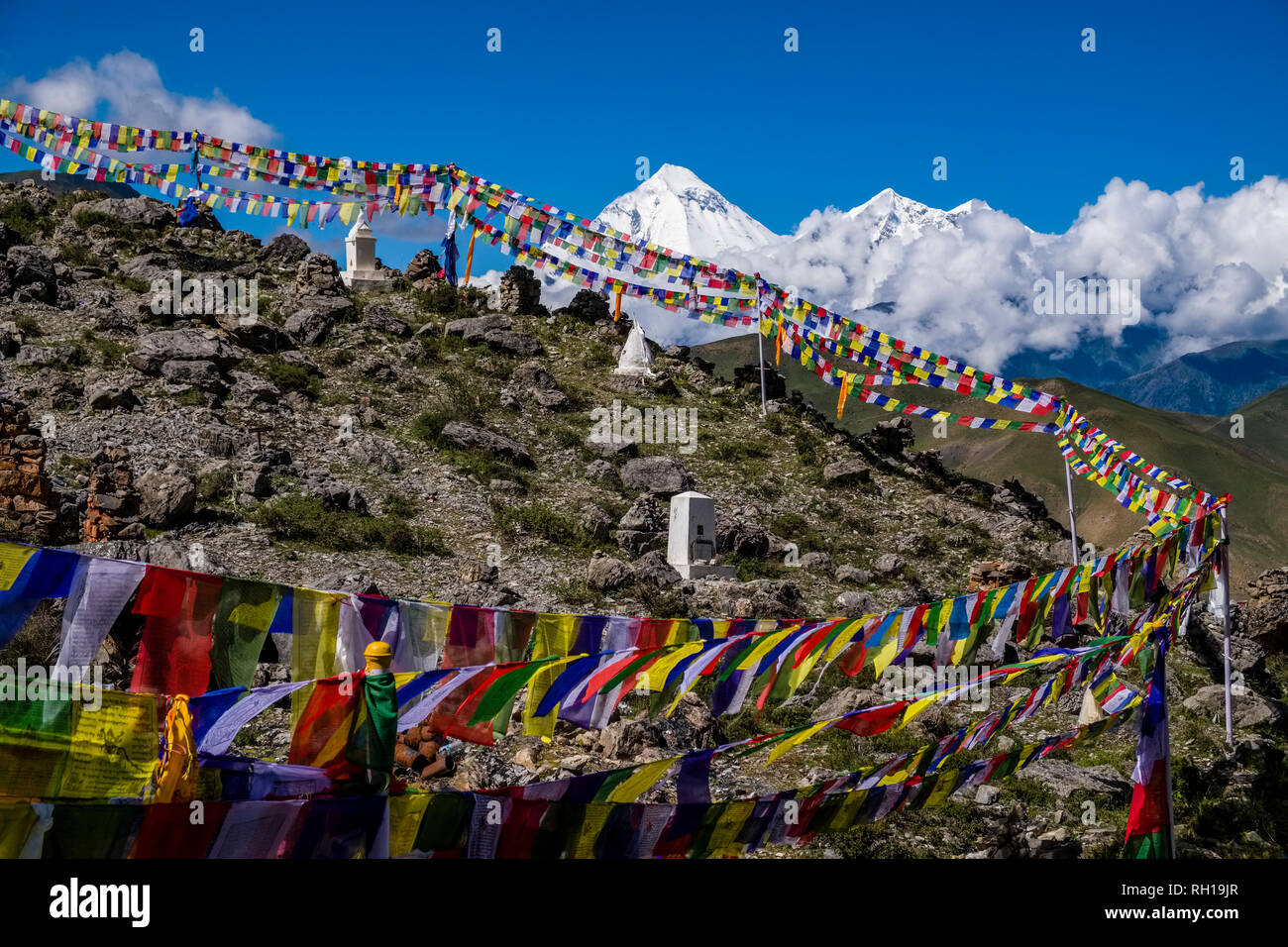 Kleiner chorten, Stupas, die über Stadt, bunten buddhistische Gebetsfahnen flattern in der Luft, der schneebedeckte Gipfel des Mt. Dhaulagiri in der Stockfoto