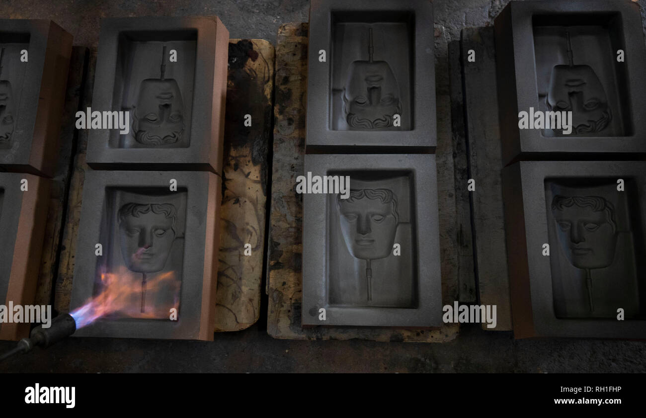 Der sand Gussteile werden in Brand gesetzt, wie sie bereit sind, für das Metall in der Hand gegossen zu werden - aus Gießen der Britischen Akademie für Film und Fernsehen Awards (BAFTA) Masken in einer Gießerei in West Drayton, London vor der Preisverleihung am 10. Februar. Stockfoto