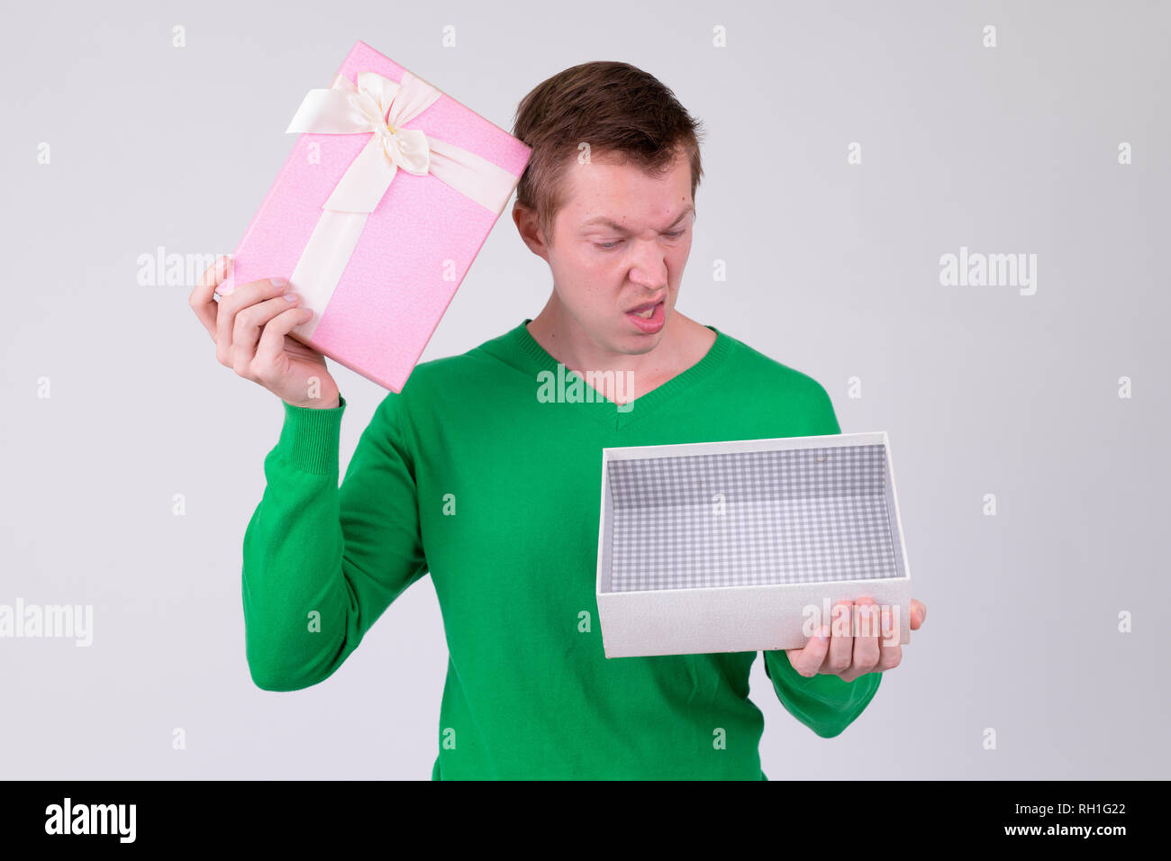 Verwirrte junge Mann hält und auf leere Geschenkbox, Stockfoto