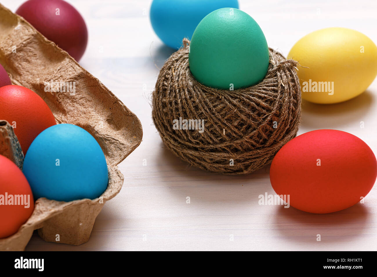 Ostern Komposition. Multi-Eier in einer Box farbig, in ein Nest von Hanf Threads, auf einem weißen Tisch." Stockfoto