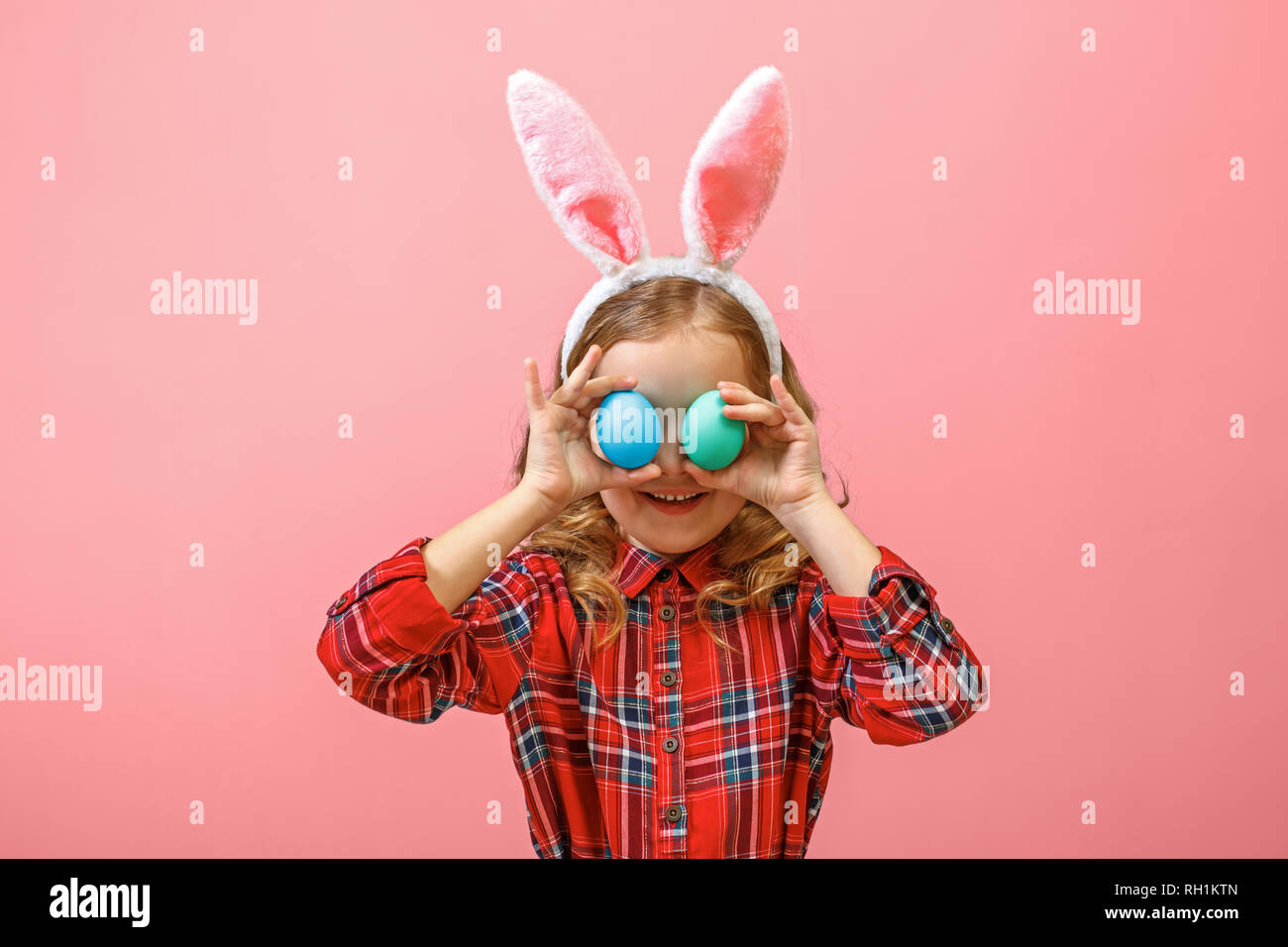 Fröhliche kleine Kind Mädchen mit Hasenohren mit zwei Ostereier auf einen farbigen Hintergrund. Stockfoto