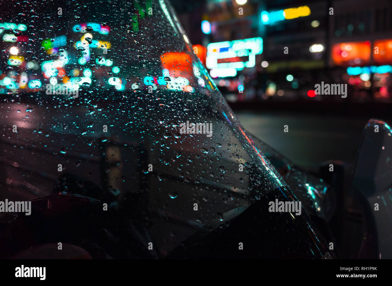 Abstract Night city unscharfen Hintergrund, bunte Reflexionen und Regentropfen auf nassen Windschutzscheibe Stockfoto